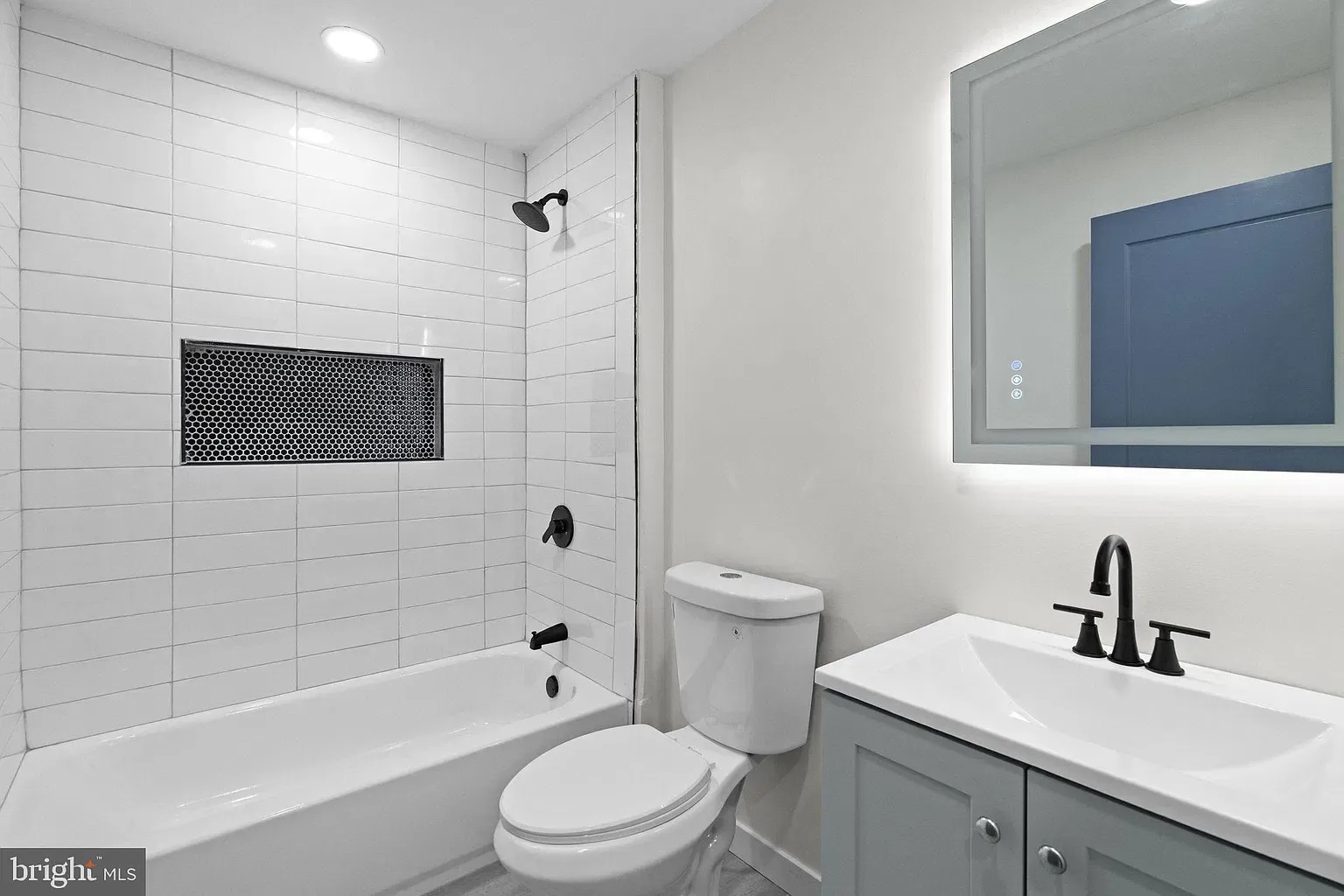 Unit A bathroom with bathtub, tiled surround, vanity, and mirror