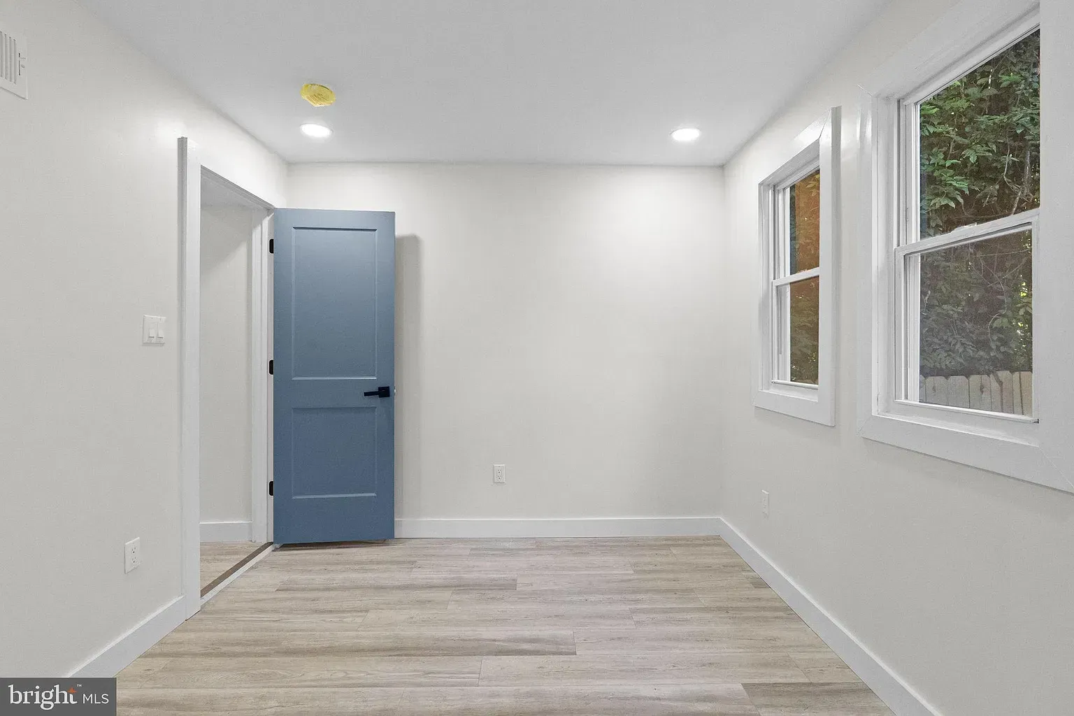 Unit A bedroom with wood-look flooring and bright white walls