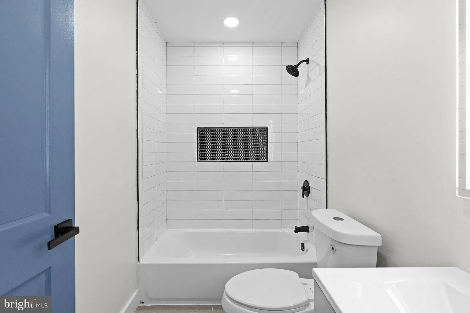 Unit B bathroom with blue door and white tile tub surround
