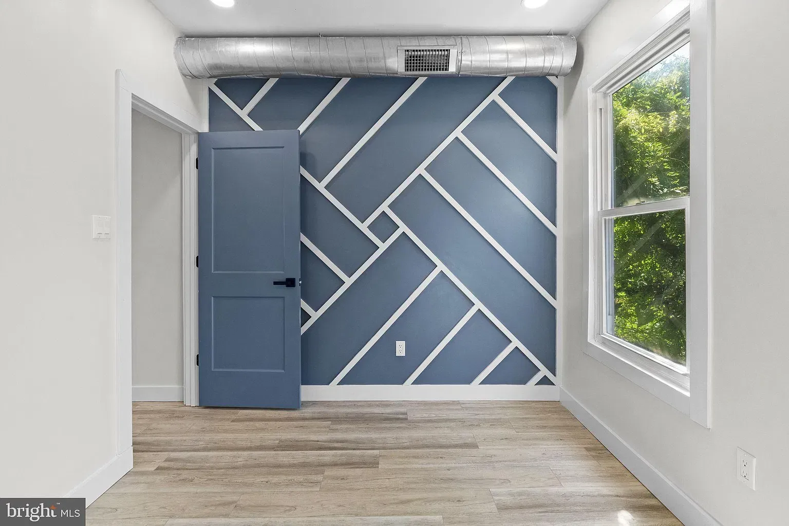 Unit B bedroom with a blue geometric accent wall and window