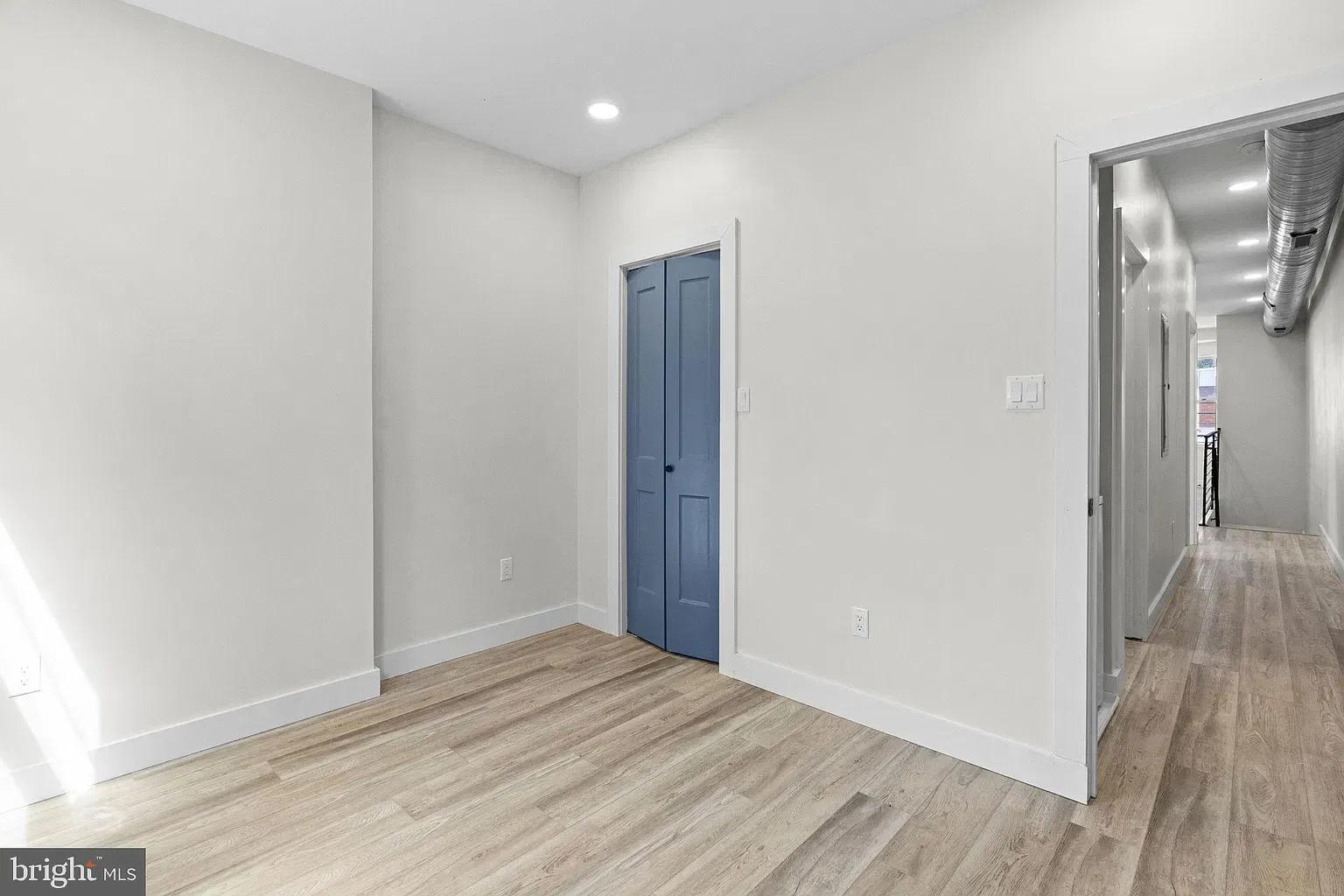 Unit B room entrance with blue door and wood-look flooring