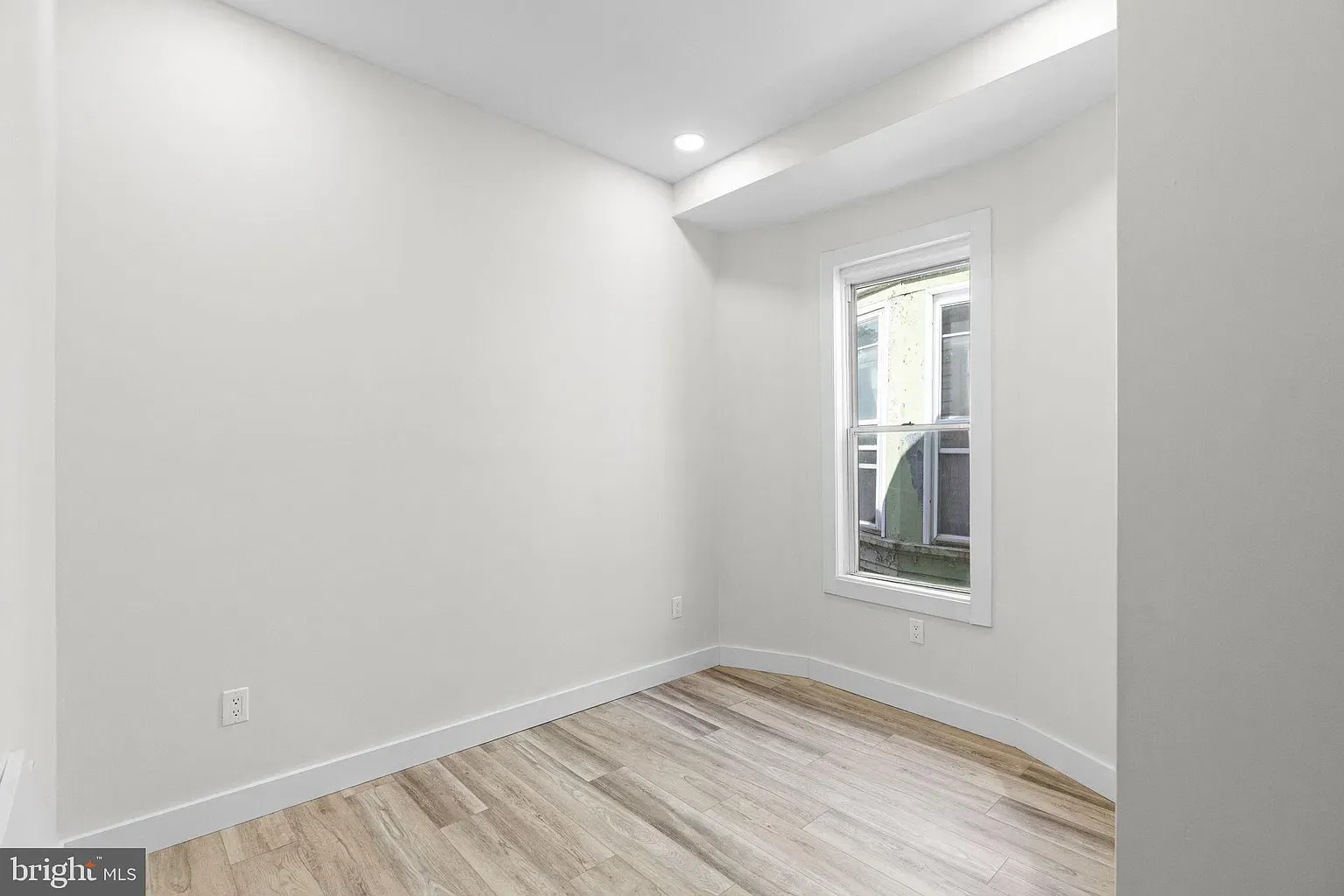 Unit B room with a window and light wood-look flooring